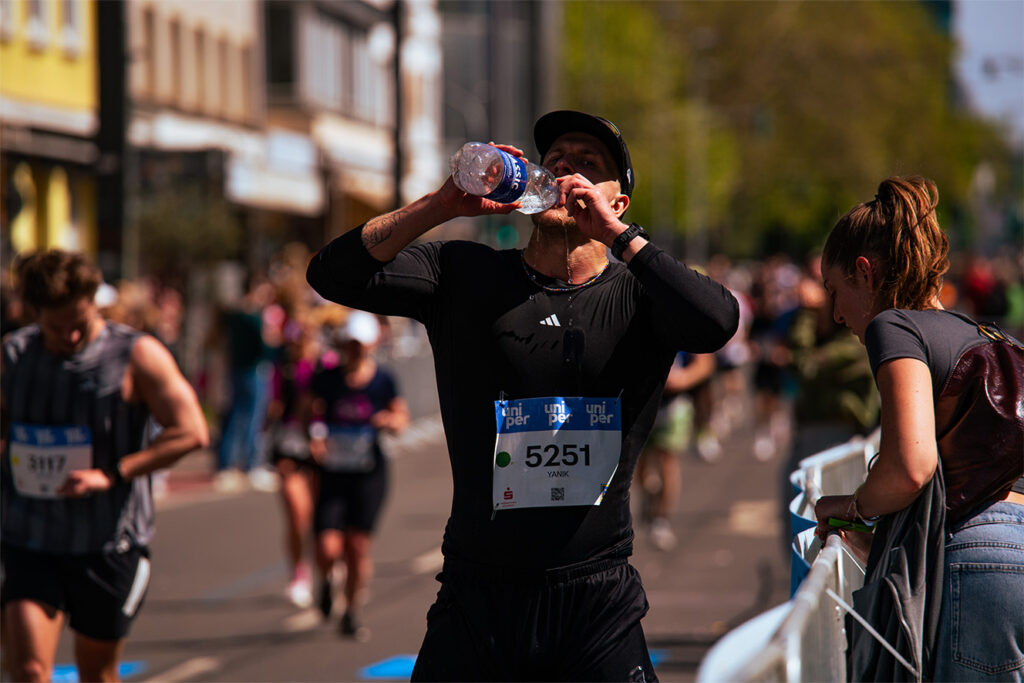 Marathonläufer trinkt Wasser während eines Laufs in Düsseldorf