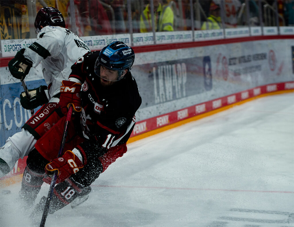 Eishockeyspieler im Zweikampf an der Bande